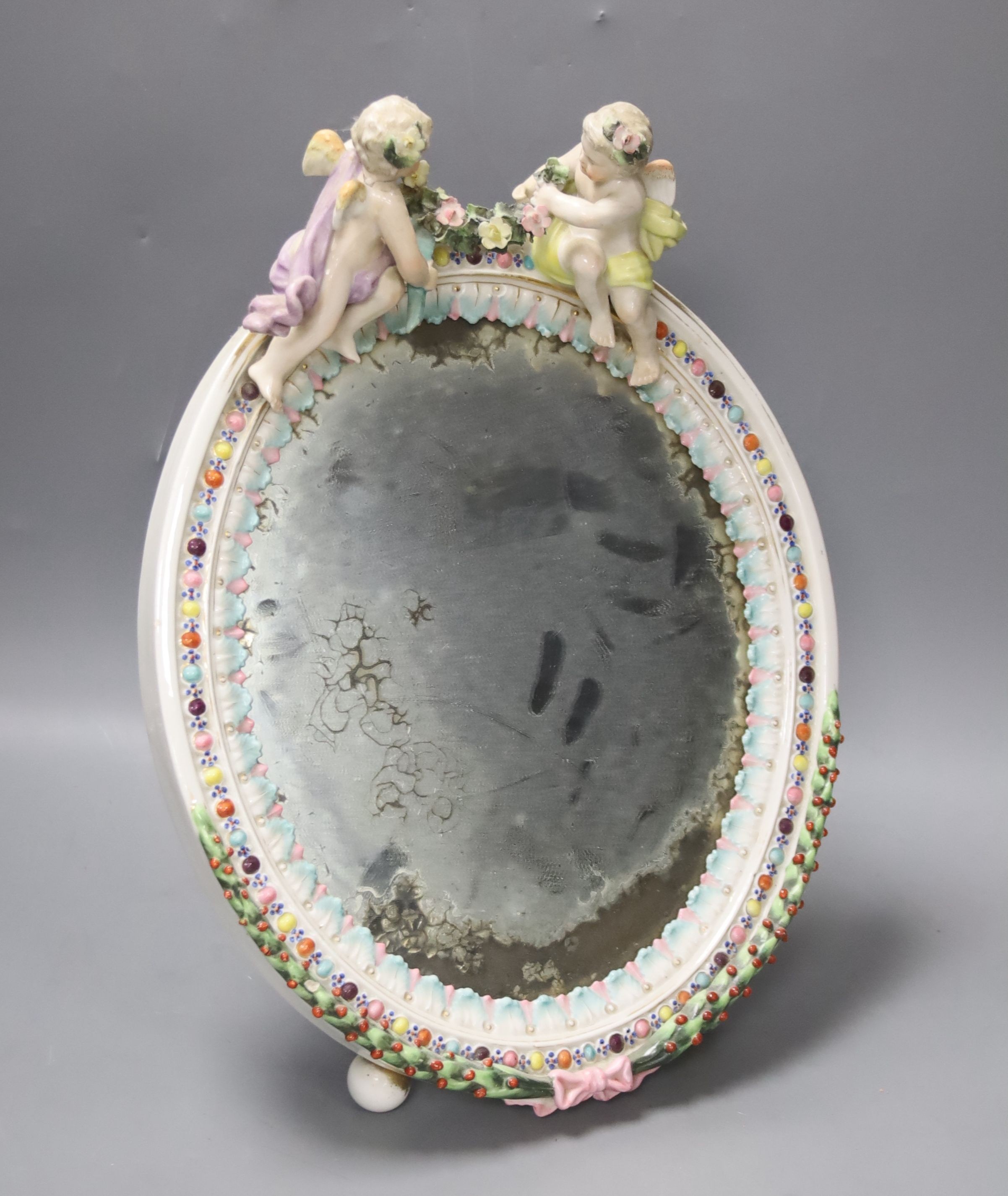 A pair of 19th century German porcelain three branch candelabra (a.f.) and an oval porcelain framed wall mirror (3)